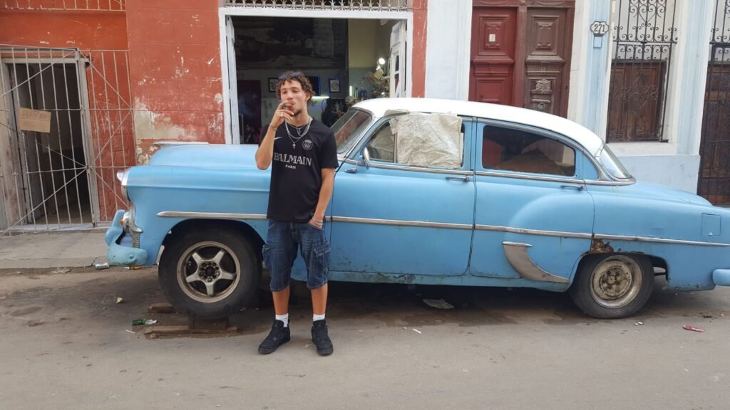 Ty against broke-up classic car in Havana Old Town