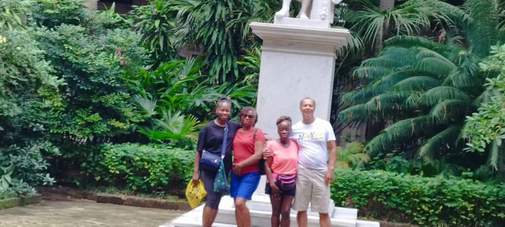 Travellers pose at statue in Havana